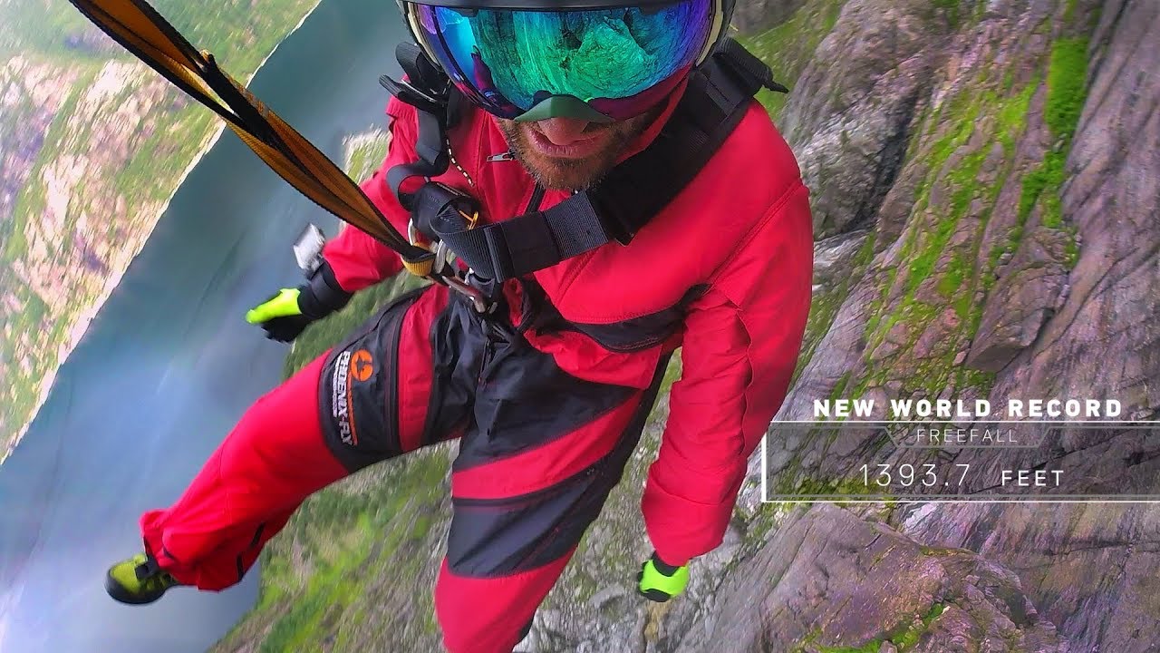 A man dangles over a cliff by rope.